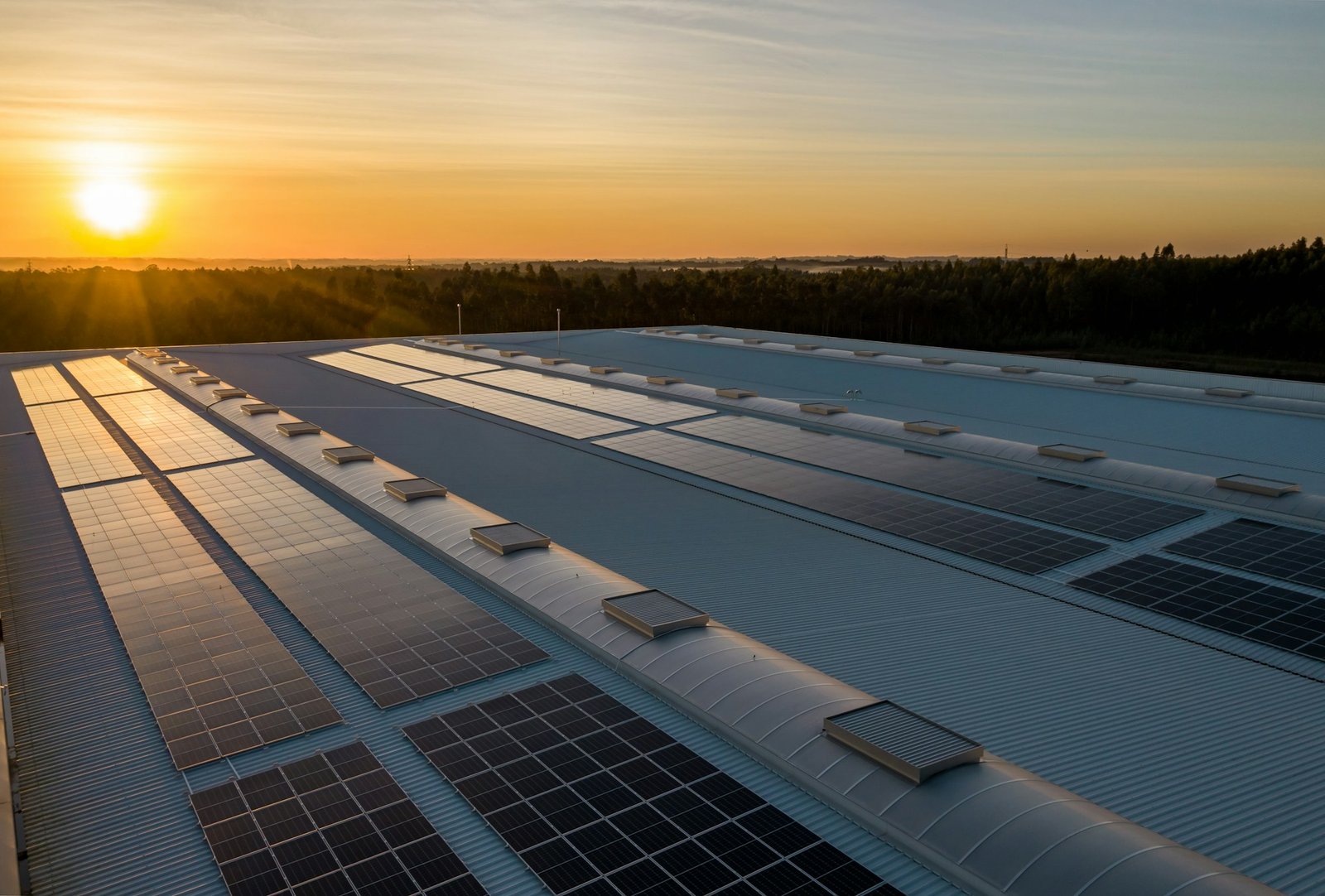 Usina solar em telhado industrial ao pôr do sol